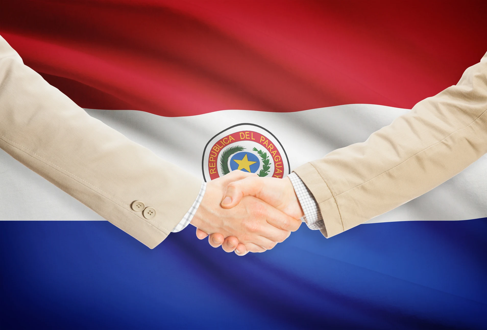 Aperto de mãos diante da bandeira do Paraguai