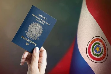 Passaporte brasileiro diante da bandeira do Paraguai